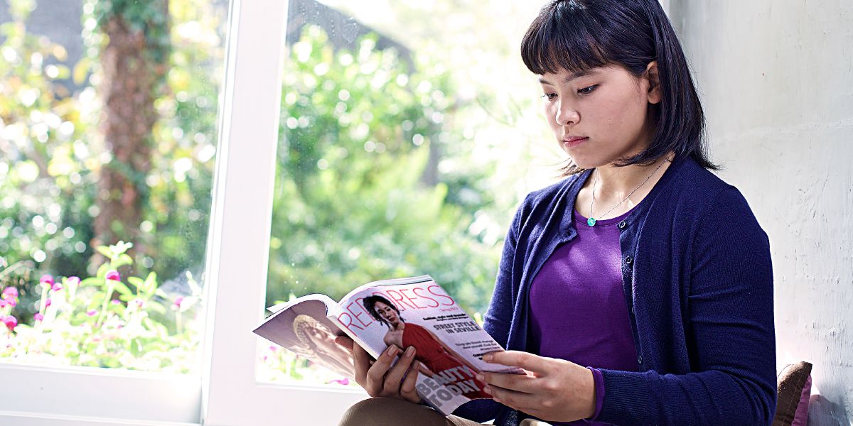 Hiji budak awéwé keur ningalian majalah