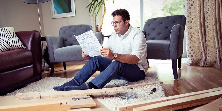 En man läser monteringsanvisningarna innan han sätter ihop en möbel.