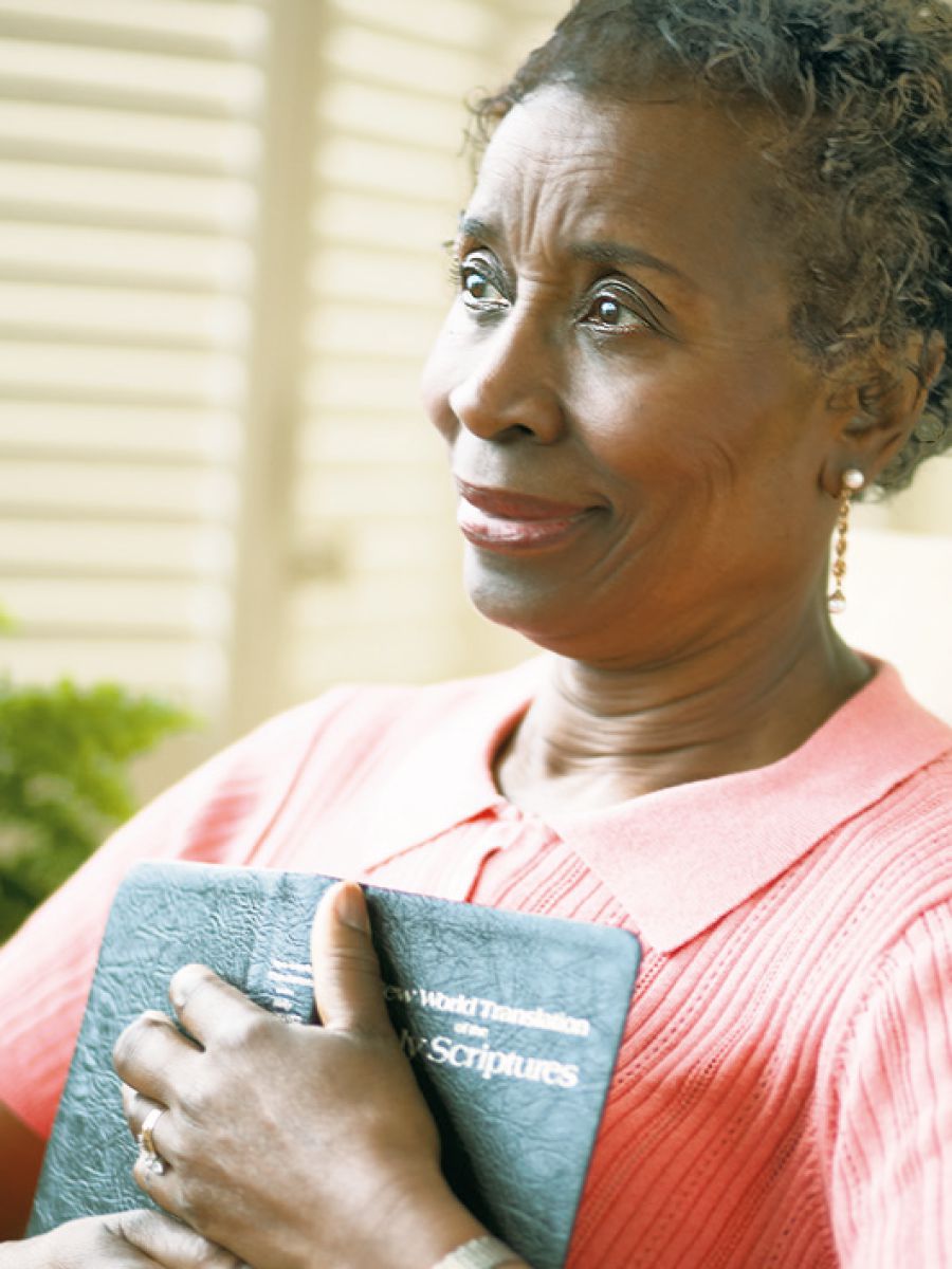 En kvinna håller om sin bibel och ler