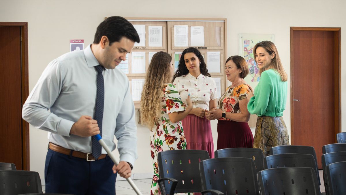 Isang dalagang sister na nakikipagkuwentuhan sa iba pang sister. Napansin niya ang isang binatang brother na naglilinis sa Kingdom Hall.