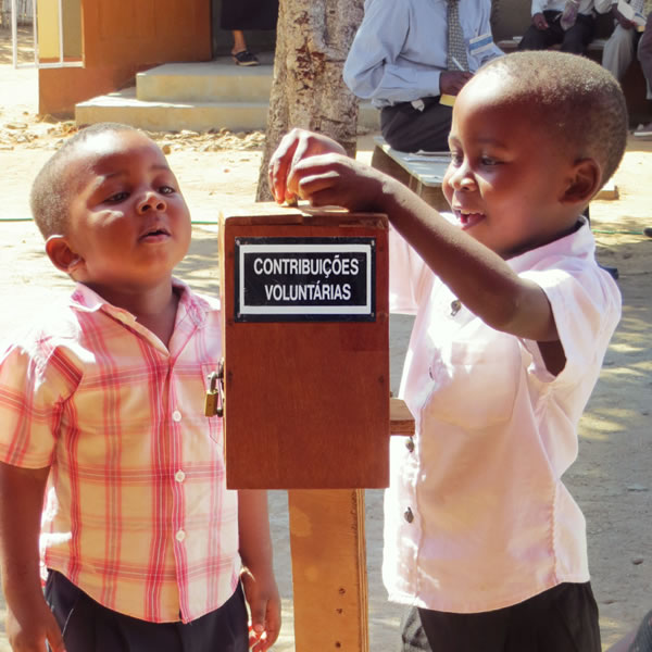 İki çocuk bağış kutusuna para atıyor