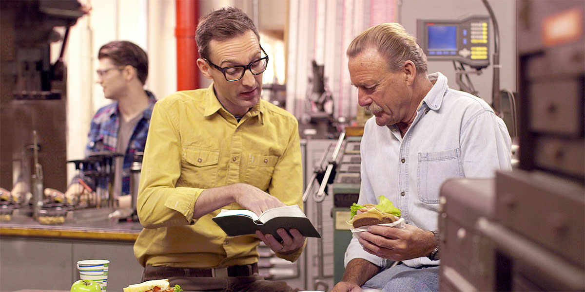 Un fradel l’è drio leder un testo dela Bìblia par un omo nel so laoro nela ora del disnar.