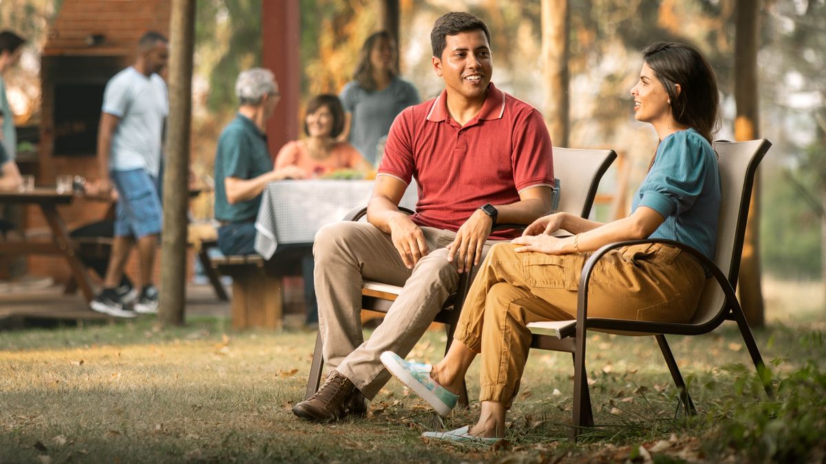 Un casal de morosi sentadi insieme drio sciacolar intanto che ghen’è altri fradei drio magnar in fondo.