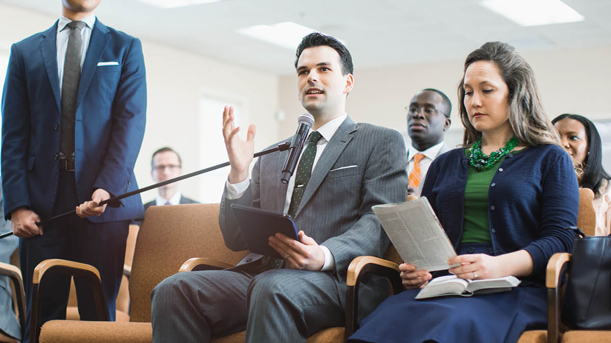 Un fradel l’è drio far un comentàrio nte una riunion.