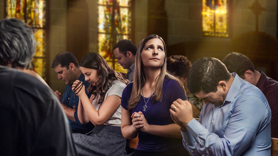 Una dona la ze in ciesa e la prega drio vardar in su intanto che i altri i prega cola testa bassa.